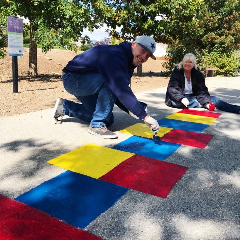 Volunteers painting a colorful hopscotch. 